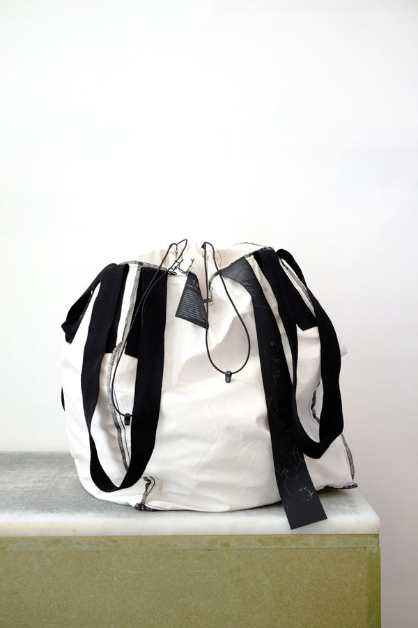 white soil sack with black fabric handles, against a white background.