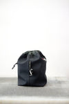 Grey drawstring bag with black drawstrings and GR10K logo patch, against a plain white wall.