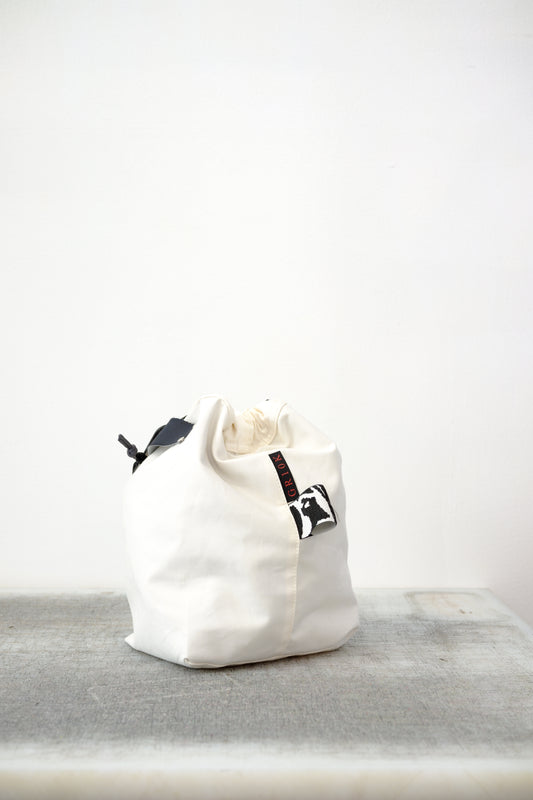 white drawstring bag with white drawstrings and GR10K logo patch, against a plain white wall.