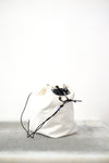 white drawstring bag with white drawstrings and GR10K logo patch, against a plain white wall.