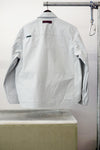 Gray utility overshirt with a pointed collar, button front, and two large chest flap pockets, hanging on a black hanger against white background