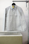 Gray utility overshirt with a pointed collar, button front, and two large chest flap pockets, hanging on a black hanger against white background