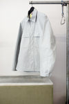 Gray utility overshirt with a pointed collar, button front, and two large chest flap pockets, hanging on a black hanger against white background