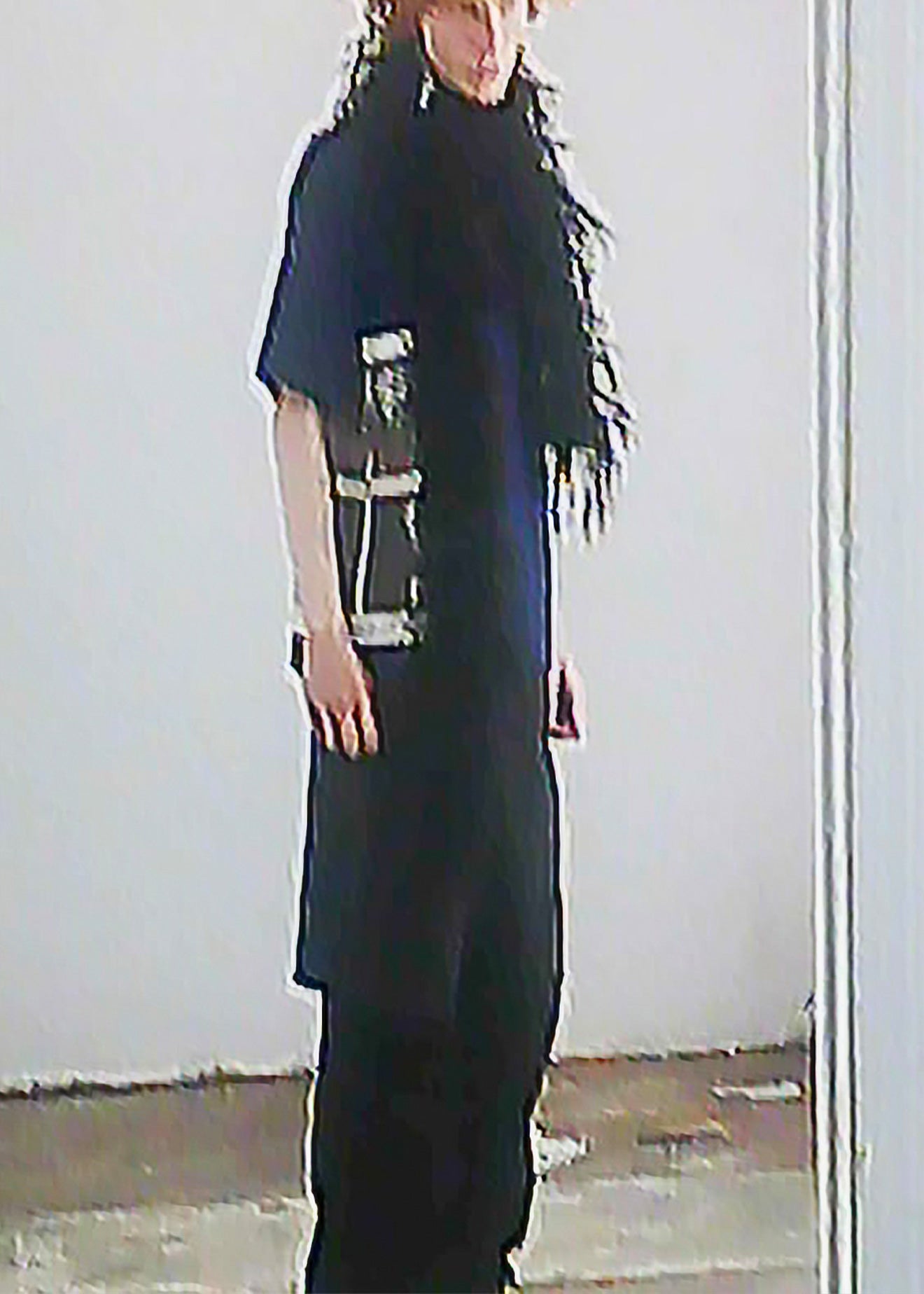 Model wearing a black outfit with a long black feathered scarf, standing against a plain light wall.