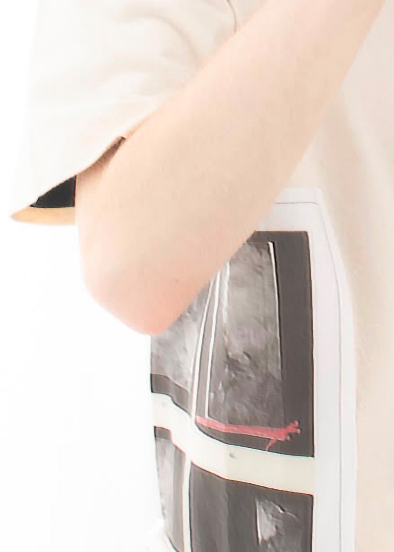 Close-up of a person wearing a cream-colored t-shirt with a large graphic print on the front featuring black, gray, and red abstract window-like shapes.