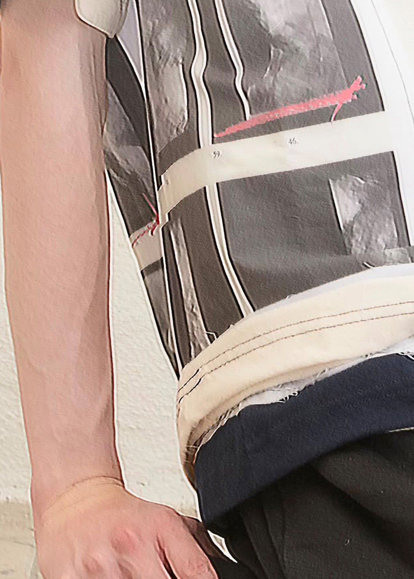 Close-up of a person wearing a sleeveless top with a black, white, and gray graphic print featuring vertical stripes and a red accent line, paired with a dark navy undershirt and dark pants.