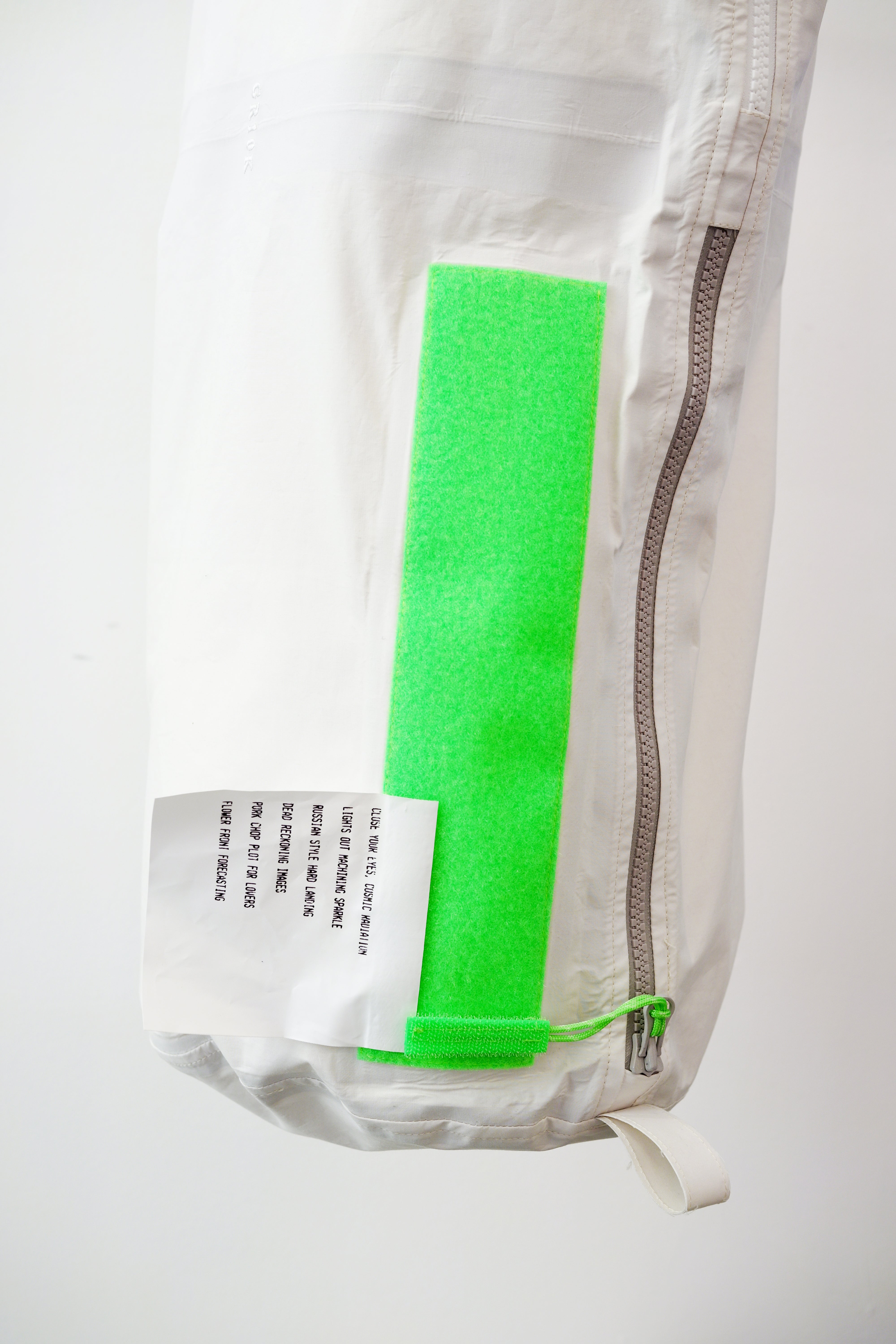 white kit bag with a lime rectangular accent panel, against a plain white wall.