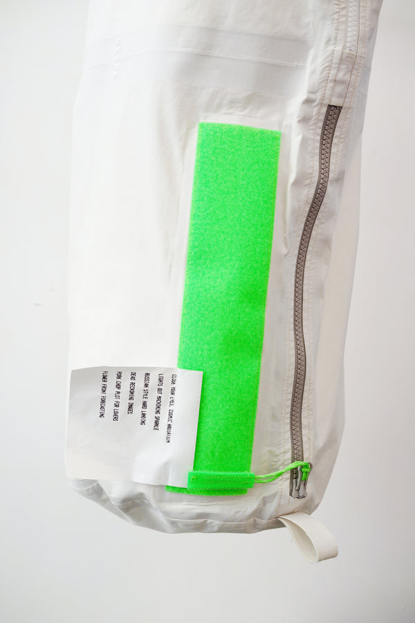 white kit bag with a lime rectangular accent panel, against a plain white wall.