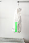 white kit bag with a lime rectangular accent panel, hanging from a black hook against a plain white wall.