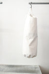 white kit bag with a lime rectangular accent panel, hanging from a black hook against a plain white wall.